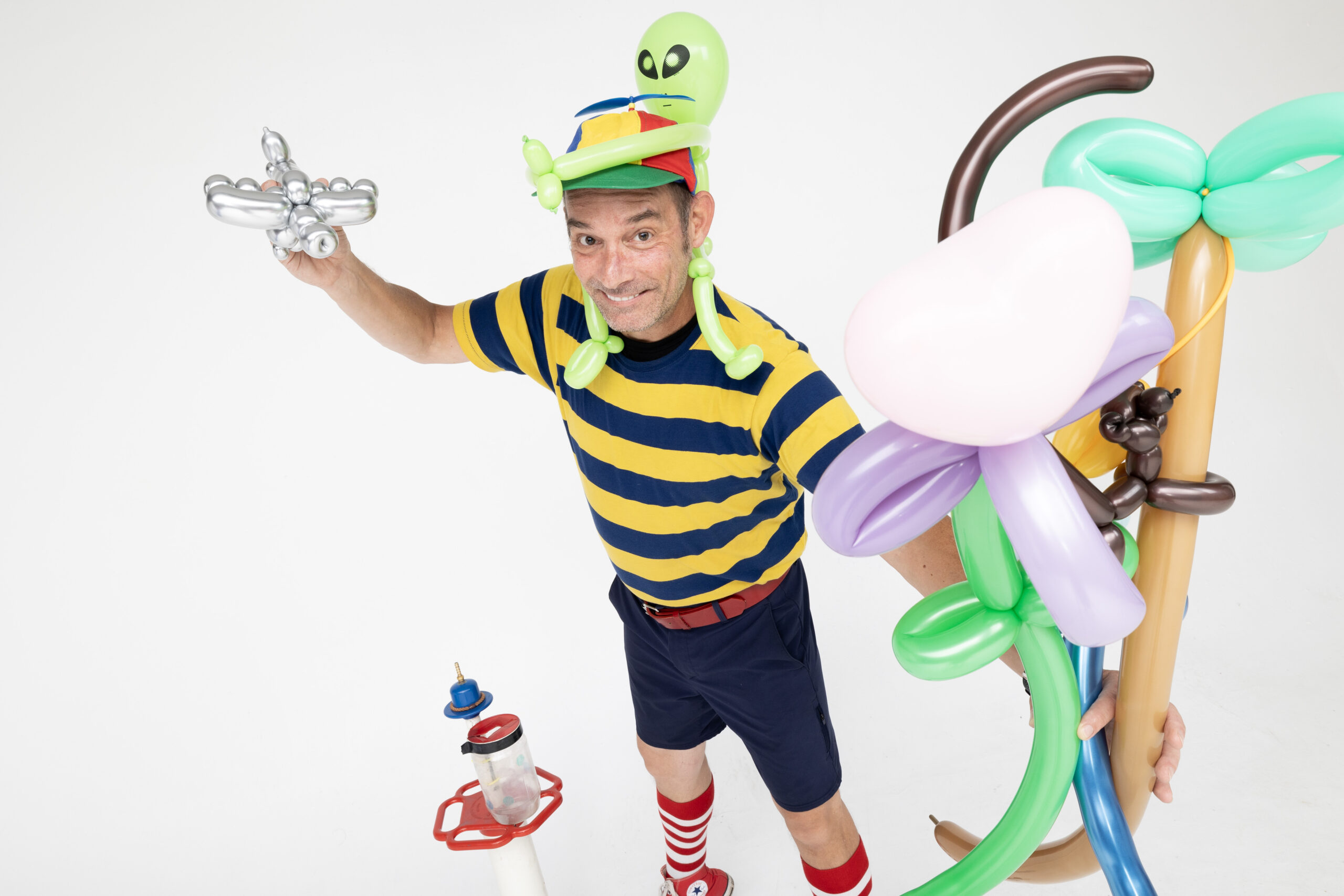 Entertainer with balloon sculptures on white background.