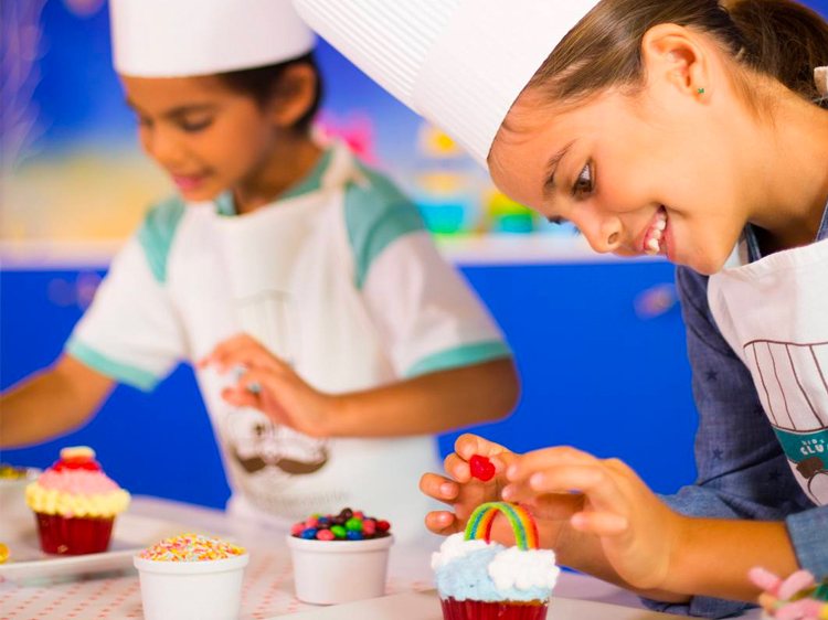 Children decorating cupcakes with colorful toppings.