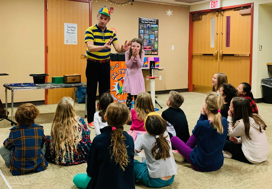 Magician performing for entertained children indoors.